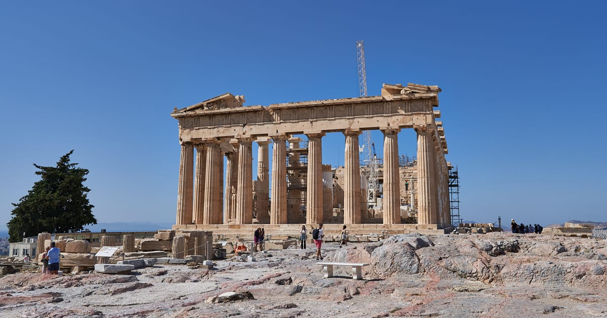 Greece tours: the Parthenon on the Acropolis of Athens seen from the east under a blue sky, with a few visitors near its base.